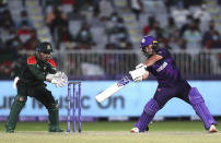 Scotland's batsman Chris Greaves, right, plays a shot as Bangladesh's wicketkeeper Nurul Hasan watches on during the Cricket Twenty20 World Cup first round match between Bangladesh and Scotland in Muscat, Oman, Sunday, Oct. 17, 2021. (AP Photo/Kamran Jebreili)