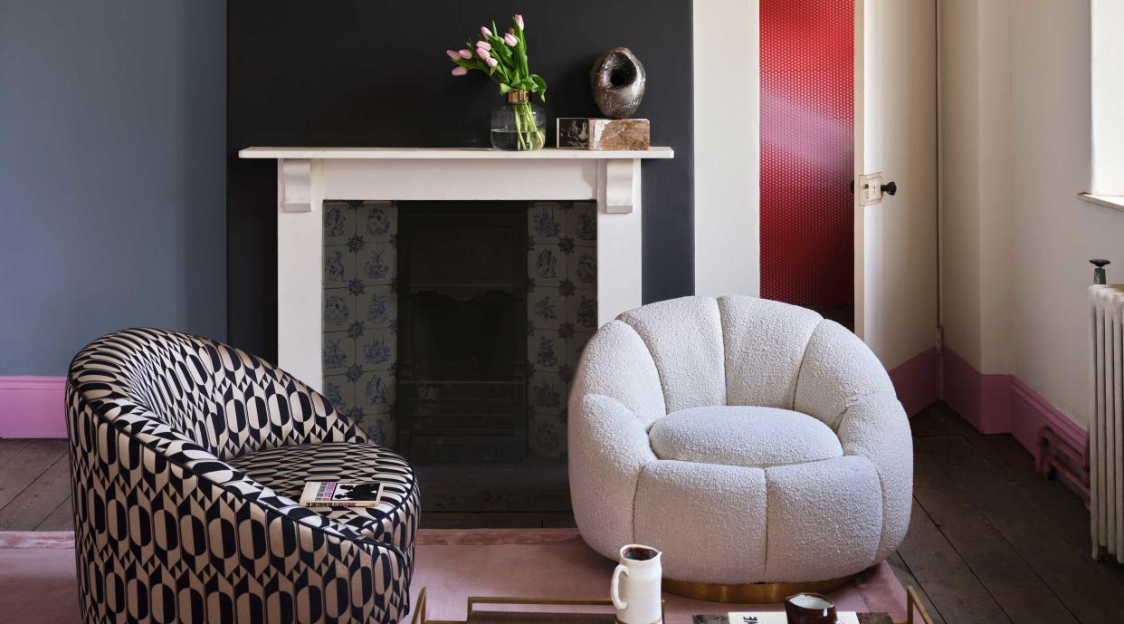  a room painted in white and black with a fireplace and comfy chairs 