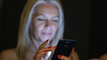 Mature woman in bed browsing mobile phone