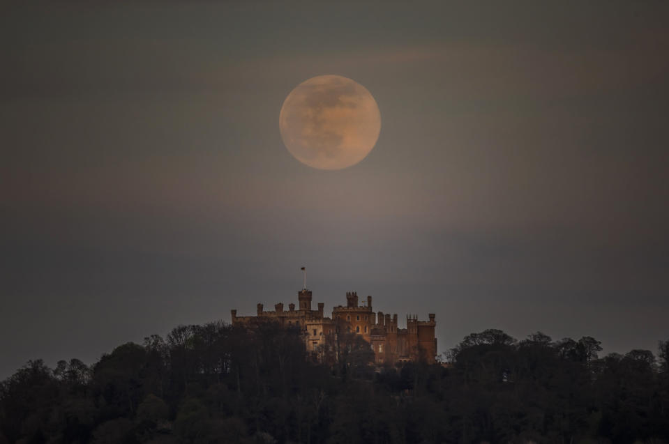 A pink supermoon is seen over Belvoir castle in Leicestershire, England, Tuesday, April 7, 2020. The phenomenon of "supermoon'' happens when the moon is at its closest point to the earth and looks larger than usual. (Danny Lawson/PA via AP)