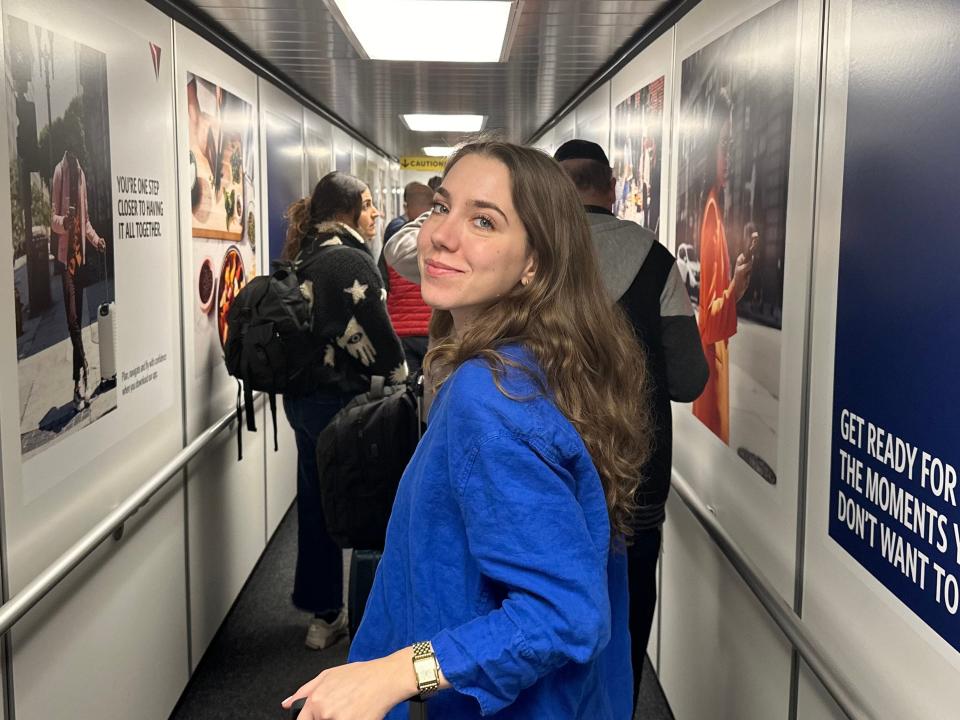 Dasha looks back at the camera while walking down a loading bridge to a plane.