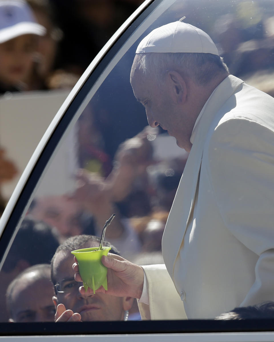 Pope Francis holds a mate gourd, a traditional South American cup, that was offered by Maximiliano Costantino a faithful from Cordoba, Argentina, as the Pontiff was touring with his popemobile St. Peter's Square on the occasion of the weekly general audience at the Vatican, Wednesday, April 16, 2014. (AP Photo/Gregorio Borgia)