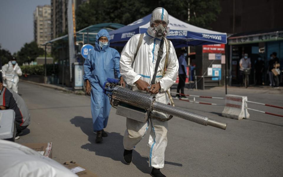 Workers wearing protective face masks and protective suits are seen as they carry out disinfection operations - Shutterstock