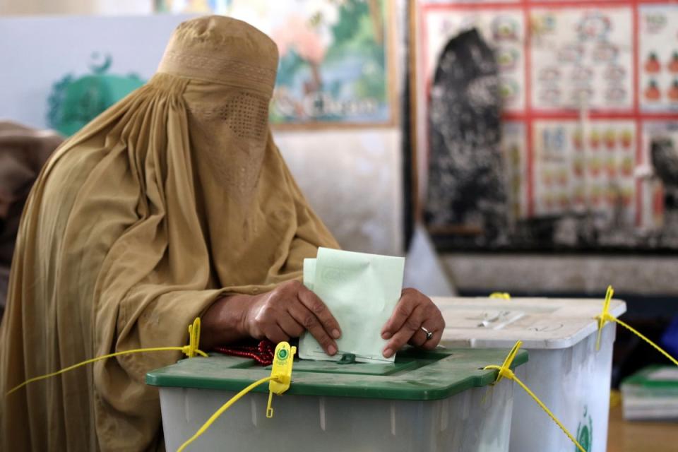 A Burqa-clad woman casts her ballot paper at a polling station during general elections in Peshawar (EPA)