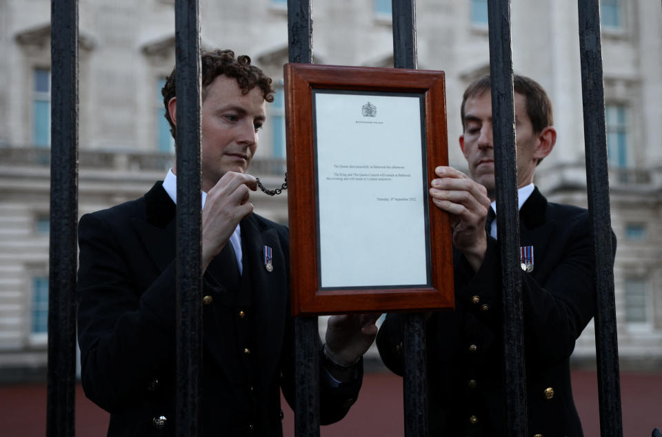 Personnel place a sign announcing the death of Queen Elizabeth on a fence outside the Buckingham Palace in London on Thursday. (Henry Nicholls/Reuters)