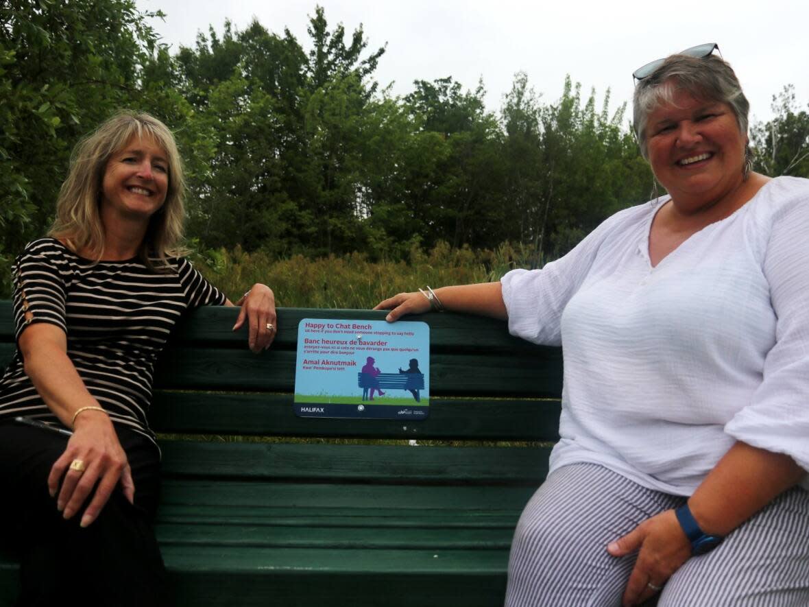 Monique Mullins-Roberts, left, and Becky Kent sit on a 'Happy to Chat' bench at Birches Park.  (Will McLernon/CBC News - image credit)