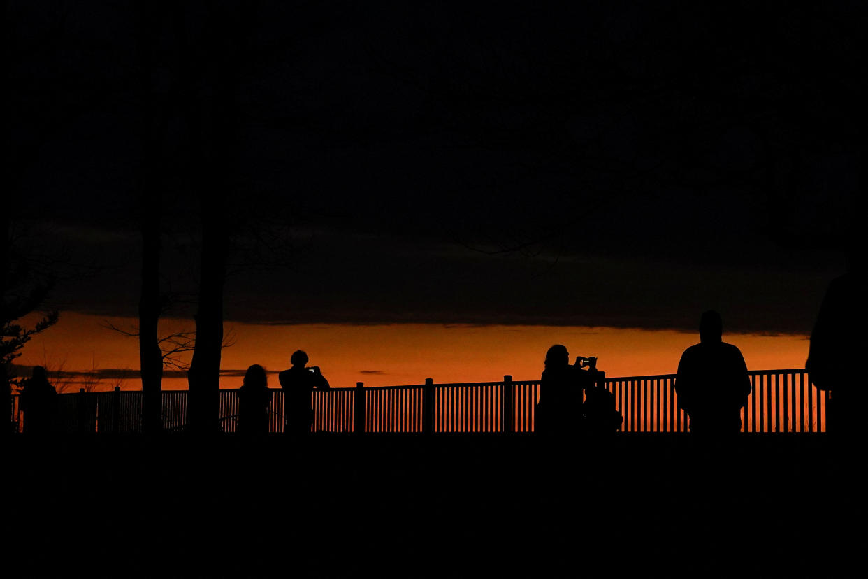 People look out toward Lake Erie and the horizon during a total solar eclipse under cloudy conditions at Dunkirk Lighthouse and Veterans Park Museum in Dunkirk, N.Y. 