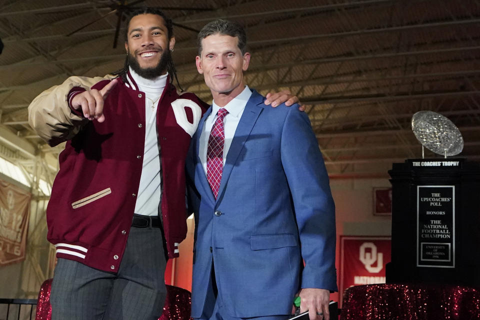 Brent Venables, right, stands with Oklahoma linebacker Caleb Kelly, left, as he is introduced at Oklahoma's new head football coach, at an NCAA college football introduction event, Monday, Dec. 6, 2021, in Norman, Okla. (AP Photo/Sue Ogrocki)