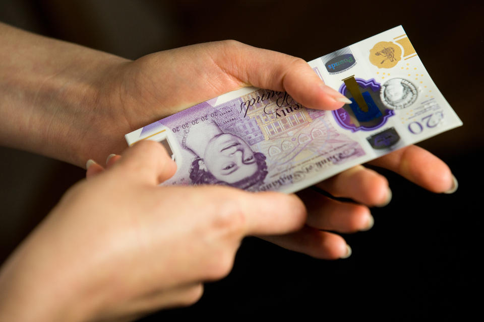 UNITED KINGDOM - 2020/06/06: In this photo illustration banknotes of the pound sterling, The Bank of England £20 notes with the image of Queen Elizabeth II are seen in a woman's hand. (Photo Illustration by Karol Serewis/SOPA Images/LightRocket via Getty Images)