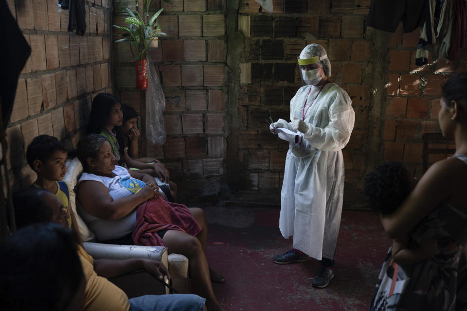 A health worker give instructions to members of Da Costa family after some of them tested positive for COVID-19 at their home in Manacapuru, Amazonas state, Brazil, Wednesday, June 3, 2020. (AP Photo/Felipe Dana)