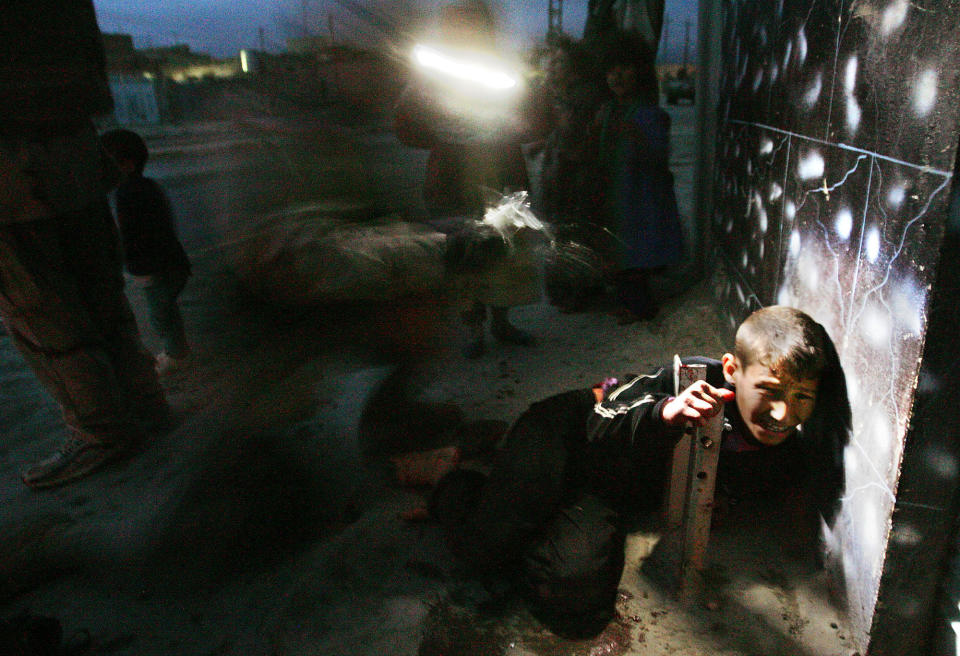 <p>Rakan Hassan, then 11, is treated by a medic seconds after being accidentally shot by U.S. soldiers January 18, 2005 in Tal Afar, Iraq. Racan’s parents were shot and killed and he was gravely wounded in the incident in the restive northern Iraqi city. The incident was widely publicized, and ultimately led to Racan’s treatment in Boston. With nerve damage to his abdomen and spine, doctors thought Racan might never walk again, but an intensive physical therapy regimen has brought back the use of his legs and he can now walk with assistance. Racan was returned to Iraq with his siblings. (Photo by Chris Hondros/Getty Images) </p>