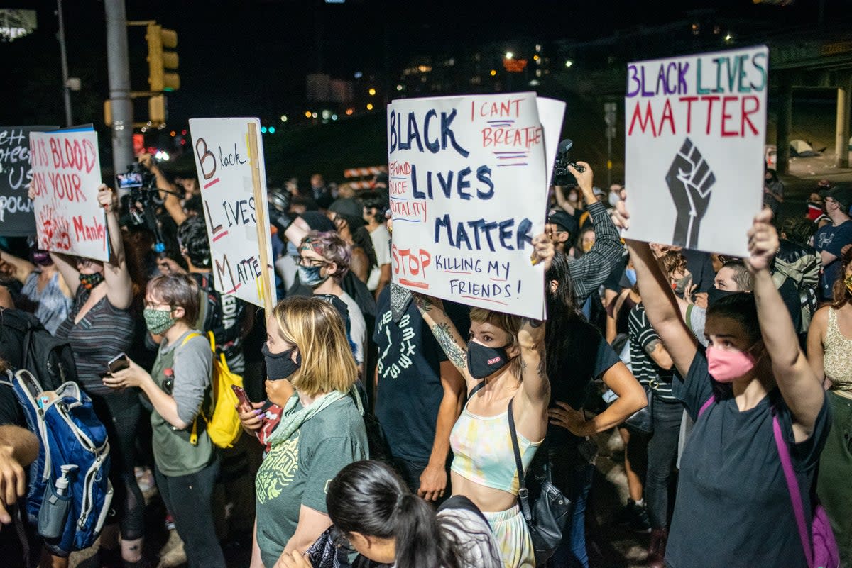 People hold up signs outside Austin Police Department after a vigil for Garrett Foster in July of 2020 (Getty Images)