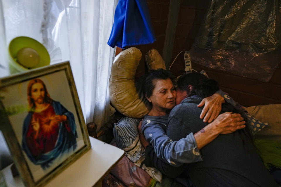 A woman embraces a relative after receiving a blessing from a priest inside her house during the Quasimodo Feast, a celebration held on the first Sunday after Easter, in Colina, Chile, April 7, 2024. The "Huasos" accompany priests to give communion to the sick, in a procession to pay tribute to the Virgin of Carmen. (AP Photo/Esteban Felix)