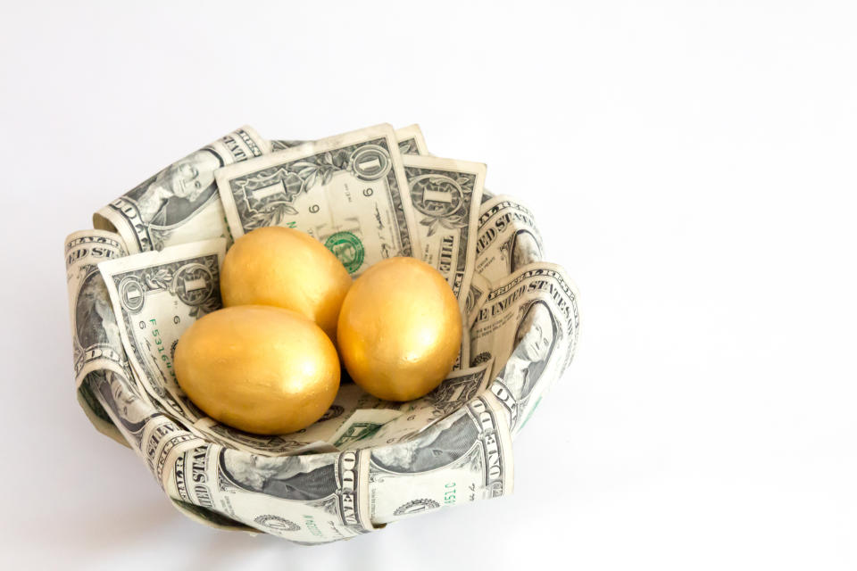 Three golden eggs in a basket lined with one-dollar bills.