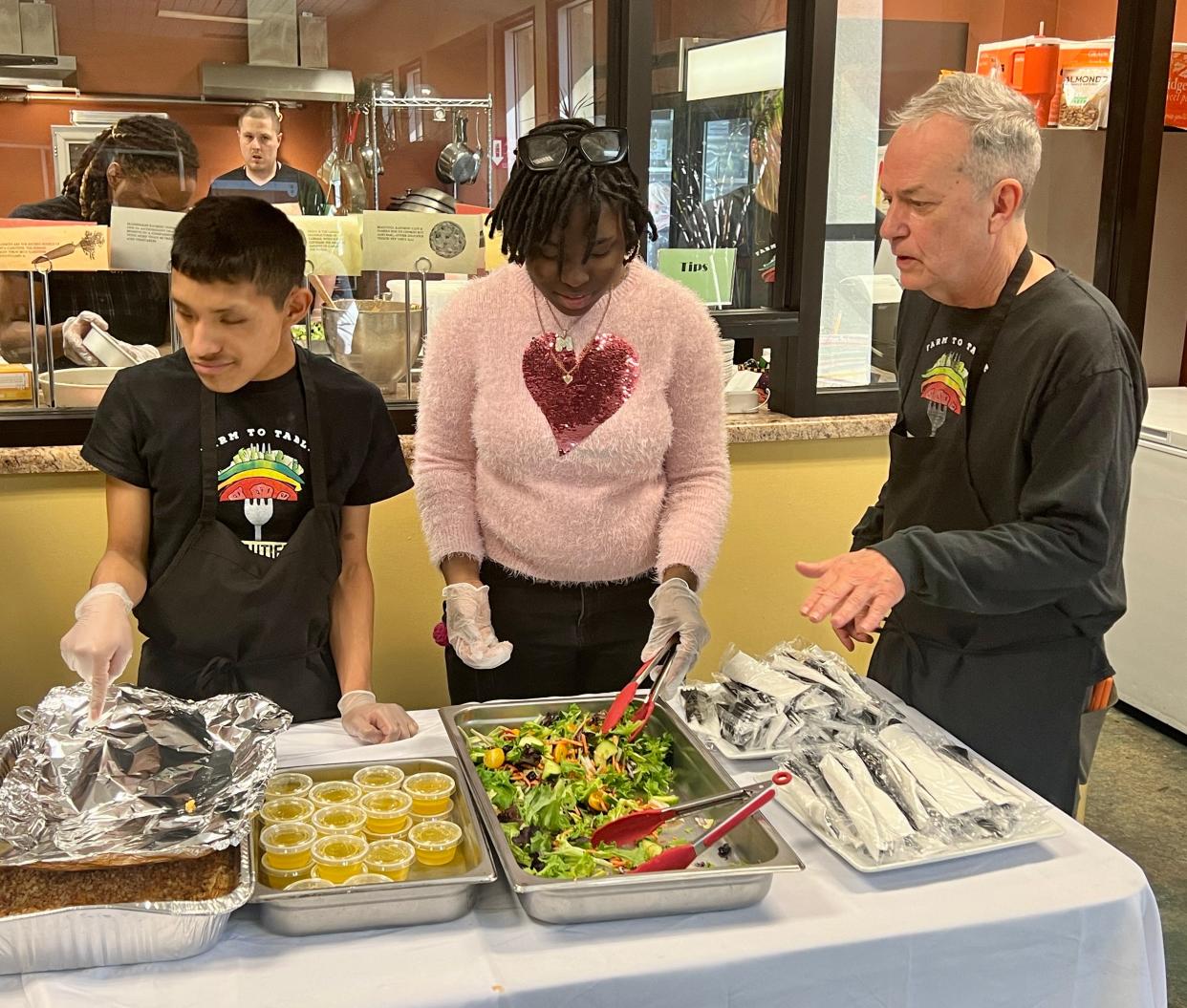 Chip Rowan, right, director of Beautiful Rainbow Cafe, instructs students Candido Lucas and Miangel Chambers during the program's seventh anniversary celebration. Beautiful Rainbow provides training in functional and workplace skills for students with cognitive disabilities.