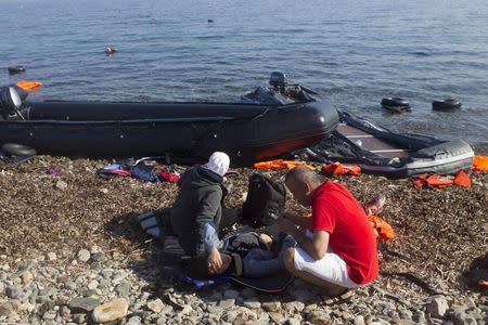 A migrant (C) lies on the beach to rest following his arrival on an overcrowded dinghy on the Greek island of Lesbos, after crossing a part of the Aegean Sea from the Turkish coast, October 5, 2015. REUTERS/Dimitris Michalakis