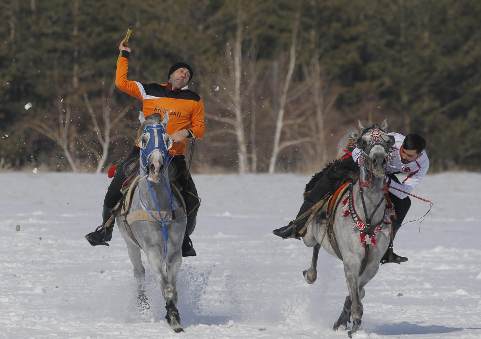 A rider throws the javelin during a game of Cirit, a traditional Turkish equestrian sport that dates back to the martial horsemen who spearheaded the historical conquests of central Asia's Turkic tribes, between the Comrades and the Experts local sporting clubs, in Erzurum, eastern Turkey, Friday, March 5, 2021. The game that was developed more than a 1,000 years ago, revolves around a rider trying to spear his or her opponent with a "javelin" - these days, a rubber-tipped, 100 centimeter (40 inch) length of wood. A rider from each opposing team, which can number up to a dozen players, face each other, alternately acting as the thrower and the rider being chased. Cirit was popular within the Ottoman empire, before it was banned as in the early 19th century. However, its popularity returned as is now one of many traditional sports encouraged by the government and tournaments are often arranged during festivals or to celebrate weddings. (AP Photo/Kenan Asyali)