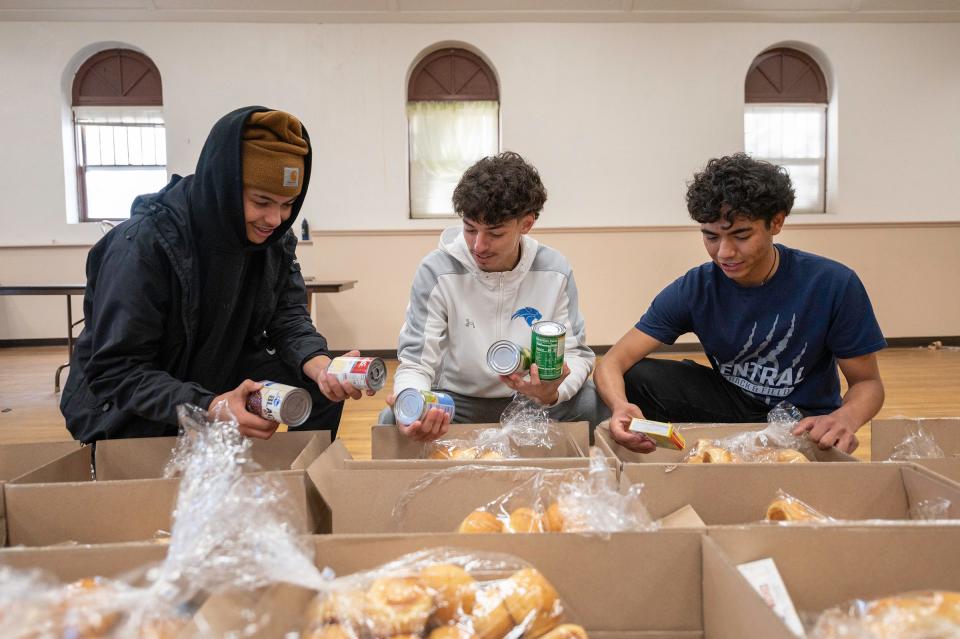 Pueblo East's Landon McAlpin, left, and Pueblo Central's Peyton Hernandez, center, and Shayen Garcia stock boxes during the Tom and Louie's Cupboard food drive at St. Joseph's Hall on Saturday, November 18, 2023.