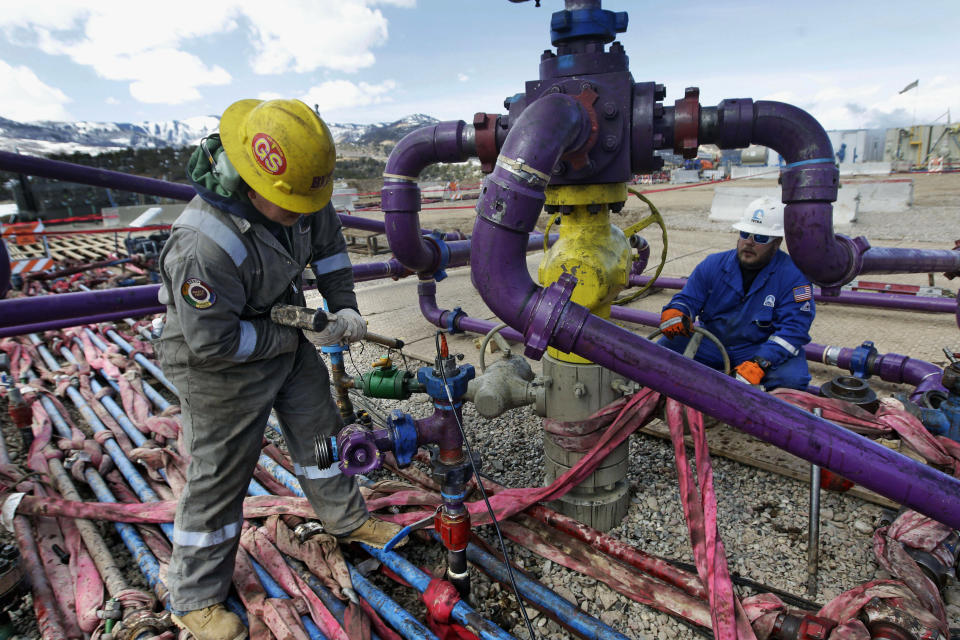 FILE - Workers tend to a well head during a hydraulic fracturing operation outside Rifle, in western Colo., March 29, 2013. Nineteen Republican state attorneys general have asked the U.S. Supreme Court to get involved in a dispute over climate-change lawsuits. (AP Photo/Brennan Linsley, File)