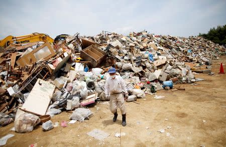 A local resident piles up household waste caused by a flooding at a temporary waste-collection point at Mabi Clean Center in Kurashiki, Okayama Prefecture, Japan, July 13, 2018. REUTERS/Issei Kato