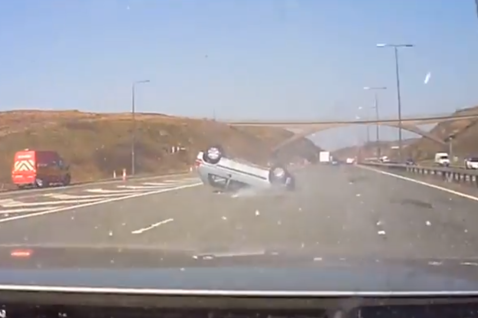 Dramatic: The footage shows the car skidding on its roof across the road (PA)