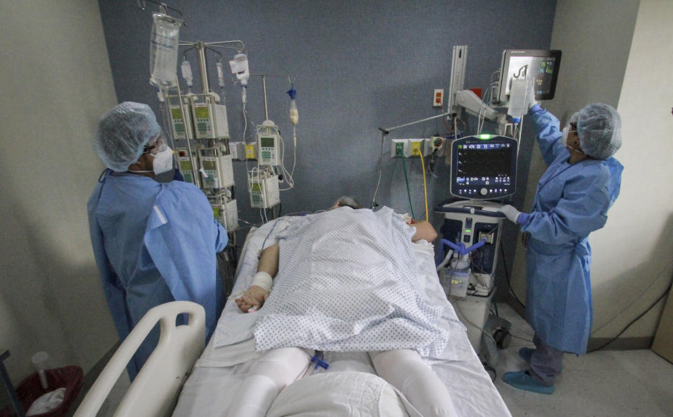 In this May 14, 2020 photo, Dr. Miguel Vazquez, left, and a medical worker, check the current status of a new coronavirus patient, in Tijuana, Mexico. Citing a threat of the coronavirus from Mexico, the Trump administration has banned hundreds of thousands of people from crossing the southern border with emergency measures that prohibit nonessential traffic and reject asylum seekers without a hearing. (AP Photo/Joebeth Terriquez)