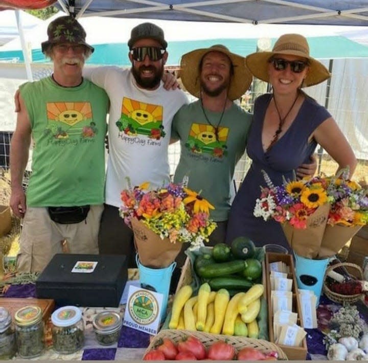 Owner of HappyDay Farms Casey O’Neill of Mendocino, third from left, stands with his wife Amber, his father Mark, left, and his brother Lito at a farmers market stand. The farm grows almost two acres of vegetables and a quarter-acre of cannabis.