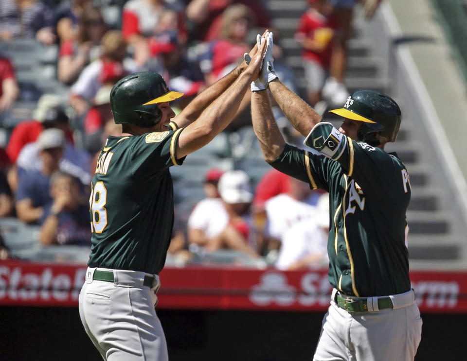 Oakland Athletics Stephen Piscotty, right, and Matt Olson celebrate as both score on Piscotty's home run against the Los Angeles Angels in the second inning of a baseball game in Anaheim, Calif., Sunday, Sept. 30, 2018. (AP Photo/Reed Saxon)