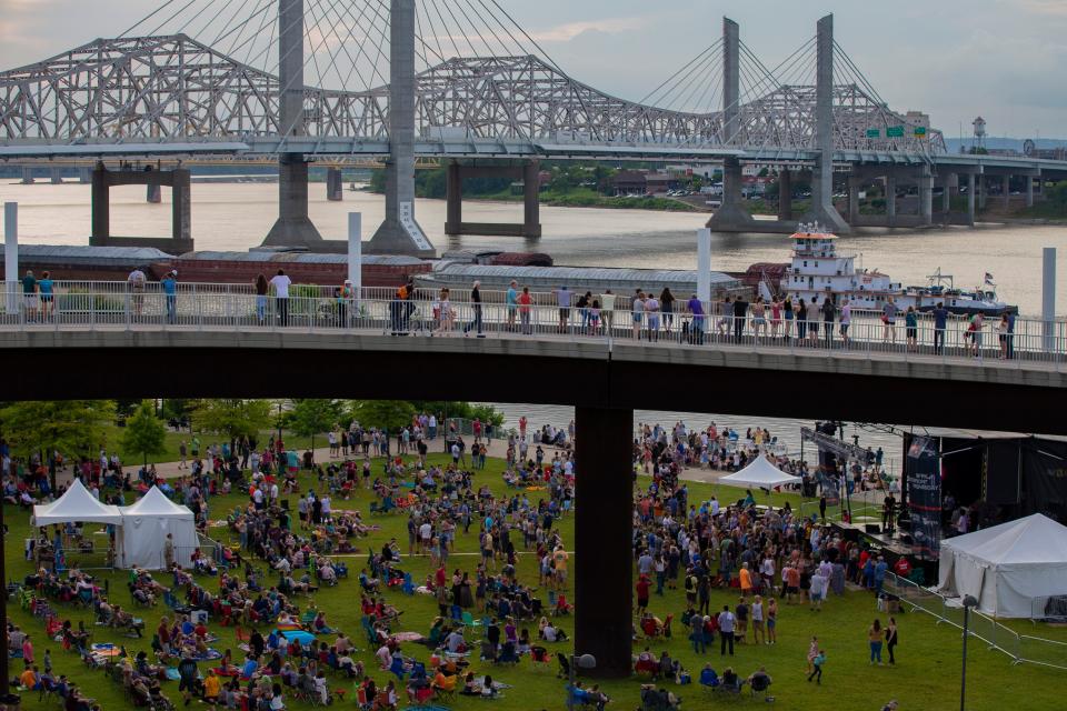 Spectators sit on the grass and look on from the Big Four Bridge during  the second Waterfront Wednesday of 2019 in Louisville, Ky. This year's concert season was canceled Wednesday because of the coronavirus pandemic.