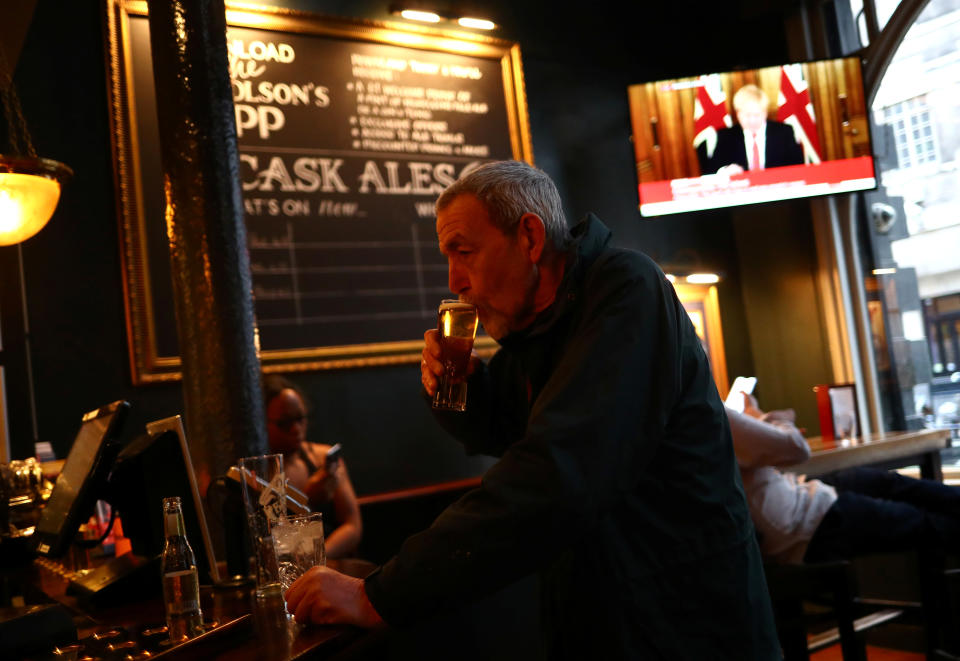 A man with a drink as Britain's Prime Minister Boris Johnson, is seen on a television screen in a pub in London as the spread of the coronavirus disease (COVID-19) continues. In Westminster, London, Britain March 20, 2020. REUTERS/Hannah McKay