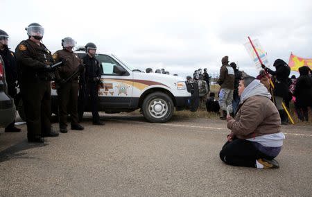 Caro Gonzales of Olympia, Washington, prays in front of police during a protest against the Dakota Access Pipeline between the Standing Rock Reservation and the pipeline route outside the little town of Saint Anthony, North Dakota, U.S., October 5, 2016. REUTERS/Terray Sylvester