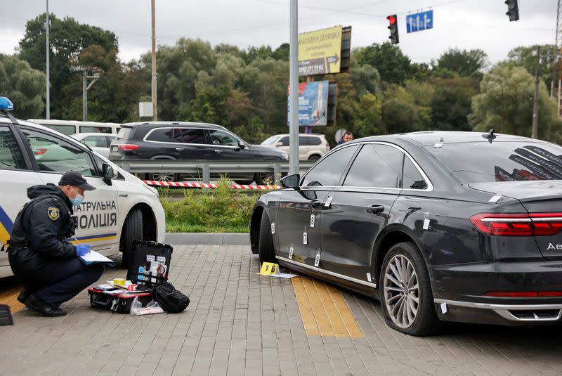 An investigator examines bullet holes in a car of presidential aide Serhiy Shefir following an assault outside Kyiv