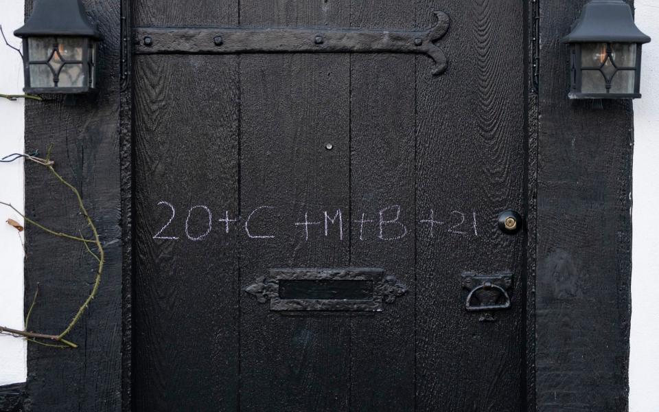 Mcc0098361. Kay and Keith Blackburn of St Peters church chalks their door as part of an epiphany tradition in Seaford, Sussex Wednesday January 06, 2021. Picture by Christopher Pledger for the Telegraph. - Christopher Pledger for the Telegraph