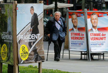 A man passes by presidential election campaign posters of Alexander Van der Bellen (L), supported by the Greens, reading "A president who unites" and Norbert Hofer of the Freedom Party (FPOe), reading "The voice of reason" in Vienna, Austria, May 19, 2016. REUTERS/Heinz-Peter Bader