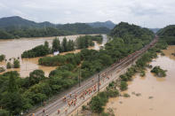 Workers gather along a section of flooded railway in Shangrao in central China's Jiangxi province, Tuesday, June 21, 2022. Major flooding has forced the evacuation of tens of thousands of people in southern China, with more rain expected. (Chinatopix via AP)