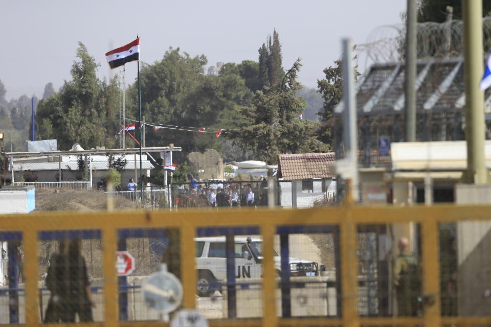 A national flag is seen on the Syrian side of Quneitra crossing from the Israeli controlled Golan Heights, Monday, Oct. 15, 2018. The crossing between Syria and the Israeli-occupied Golan Heights reopened for U.N. observers who had left the area four years ago because of the fighting there. (AP Photo/Ariel Schalit)