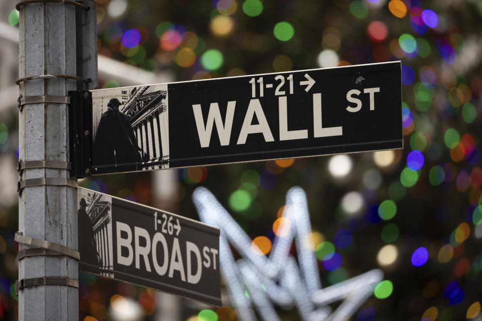 A sign at the intersection of Broad and Wall Street is shown next to holiday lights outside the New York Stock Exchange.
