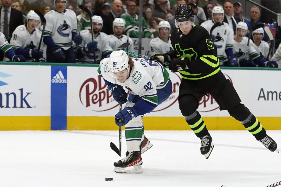 Vancouver Canucks right wing Vasily Podkolzin (92) and Dallas Stars defenseman Nils Lundkvist (5) try to get to the puck during the second period of an NHL hockey game in Dallas, Saturday, March 25, 2023. (AP Photo/LM Otero)