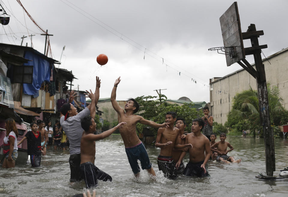 FILE - Filipino boys play basketball in floodwaters from a swollen creek at a coastal village in Malabon, north of Manila, Philippines, Wednesday, July 8, 2015. (AP Photo/Aaron Favila, File)
