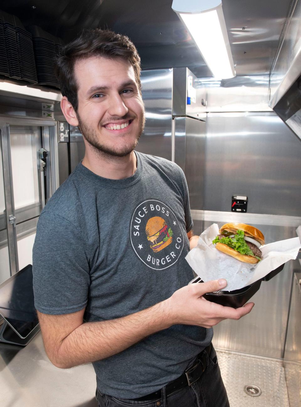 Eli Cook shows off one of his signature Sauce Boss Burger Company burgers on Tuesday, Jan. 25, 2022. The Sauce Boss Burger Co. is one of the full-time vendors operating out of the new The Eatery food truck park in Gulf Breeze. 