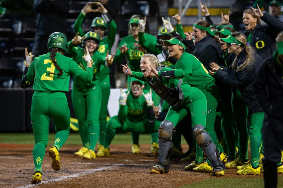 Oregon players gather at home plate to celebrate a home run by Oregon outfielder Ariel Carlson, left, during a win over Oregon State at Jane Sanders Stadium on Saturday, April 30, 2022.