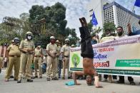 TOPSHOT - Police personnel stand guard as farmers rights organisations stage a protest following the recent passing of agriculture bills in the Lok Sabha (lower house), in Bangalore. - Angry farmers took to the streets and blocked roads and railways across India on September 25, intensifying protests over major new farming legislation they say will benefit only big corporates. (Photo by Manjunath Kiran / AFP) (Photo by MANJUNATH KIRAN/AFP via Getty Images)