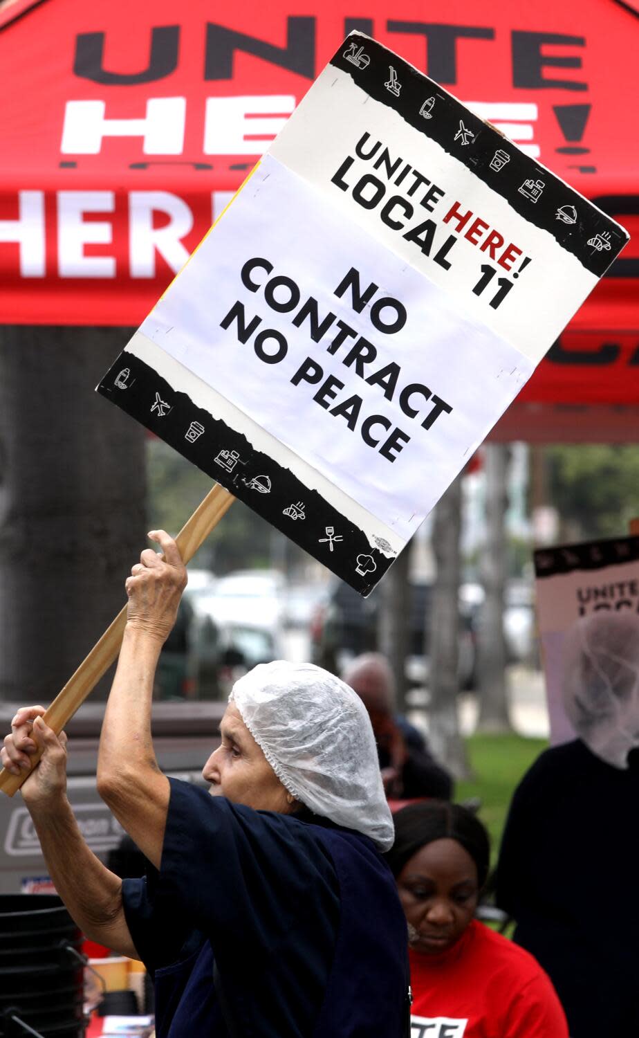 A woman carries a sign while picketing with fellow workers.