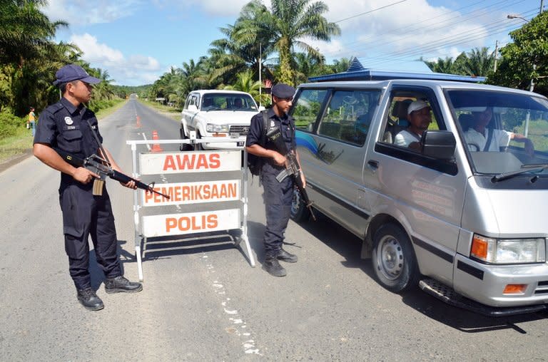 Two armed policemen man a security check post in a village of Bakapit near Lahad Datu, on the Malaysian island of Borneo on February 14, 2013. Malaysia's government said Thursday its security forces have surrounded dozens of Philippine gunmen in a remote area of Borneo island, and a report said the group is demanding the right to stay