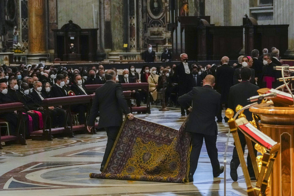 Vatican attendants remove a carpet minute before Pope Francis arrives to celebrate the 'In passione Domini' (in the passion of the Lord) mass in St. Peter's Basilica at the Vatican on Good Friday, Friday, April 15, 2022. Usually at the Good Friday basilica service at the Vatican, the pontiff would prostrate himself in prayer. But this time Francis, hobbled by pain for weeks, didn't do so. (AP Photo/Andrew Medichini)