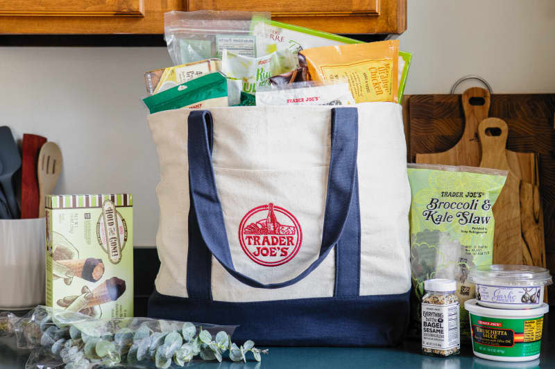 Trader Joe's canvas bag filled with groceries; some grocery items on countertop.