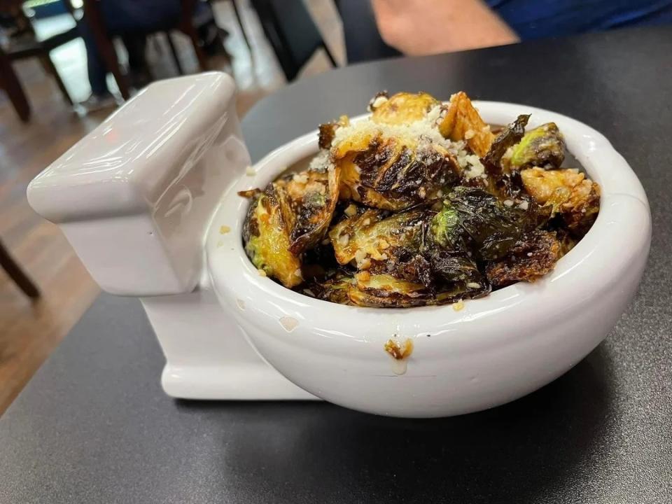 A bowl of roasted Brussels sprouts served in a small white bowl designed to resemble a toilet