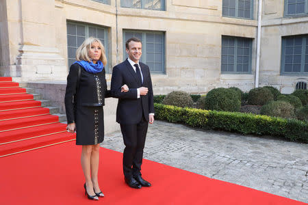 France's President Emmanuel Macron and his wife Brigitte Macron pose as they arrive at the French Institute, where Macron will unveil his strategy to promote French language as part of the International Francophonie Day, before members of the French Academy and other guests, in Paris, France, March 20, 2018. Ludovic Marin/Pool via REUTERS