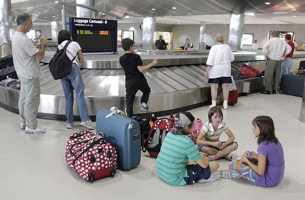 Passengers wait to get their luggage at a baggage claim area. (Photo by Bill Pugliano/Getty Images)