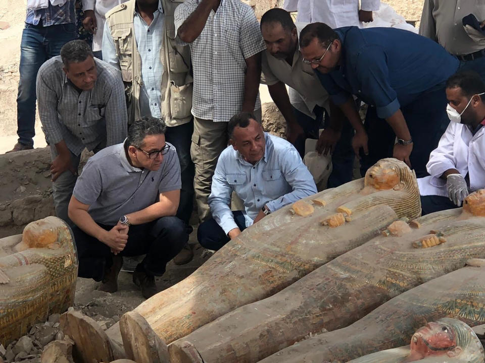 FILE - This Tuesday, Oct. 15, 2019 file photo provided by the Egyptian Ministry of Antiquities shows Egyptian Minister of Antiquities Khaled el-Anany, foreground left, looking at recently discovered ancient colored coffins with inscriptions and paintings, in the southern city of Luxor, Egypt. (Egyptian Ministry of Antiquities via AP, File)